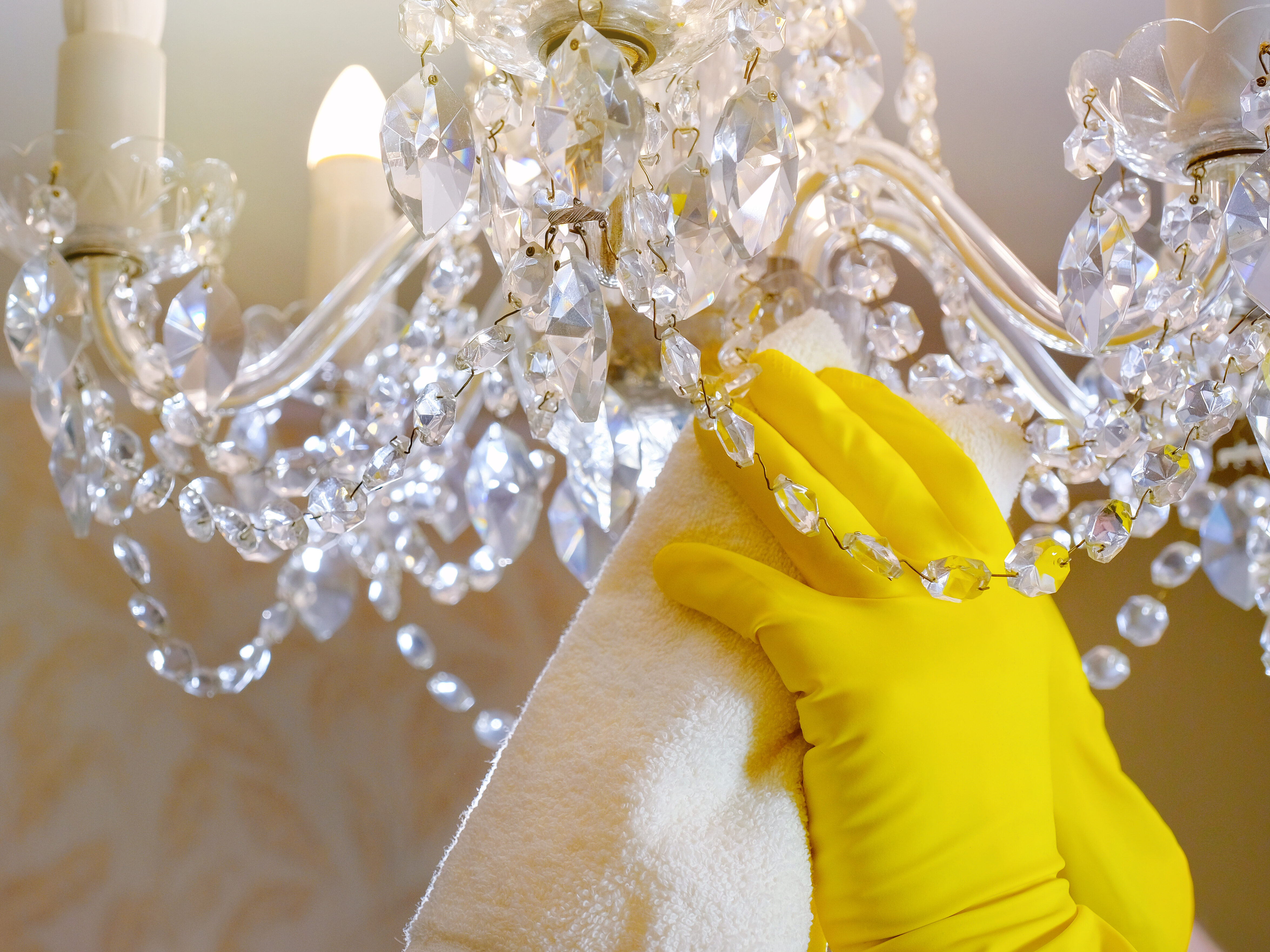 Hands in gloves clean the chandelier with a rag. Close-up. House cleaning.
